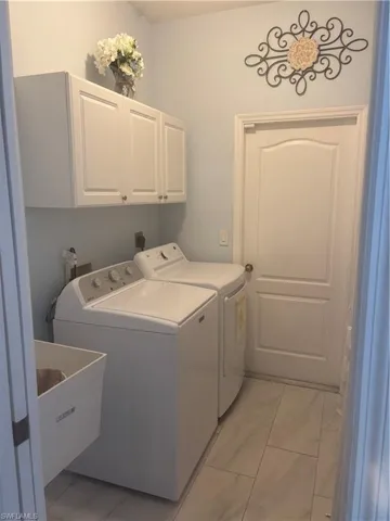Laundry area with cabinets, washing machine and clothes dryer, and sink