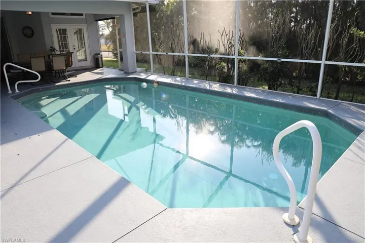 View of pool with screened-in lanai & patio.
