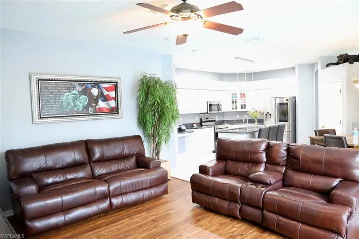 Living room featuring ceiling fan, kitchen, and wood-style vinyl floors