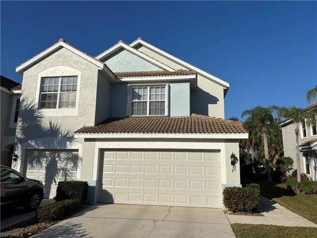 View of front facade with driveway, stucco siding, a tiled roof, and a garage