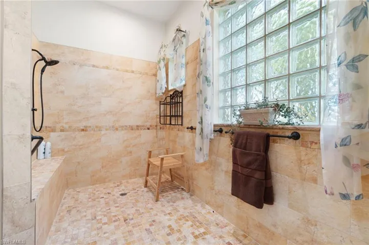 Bathroom featuring tiled shower and tile walls