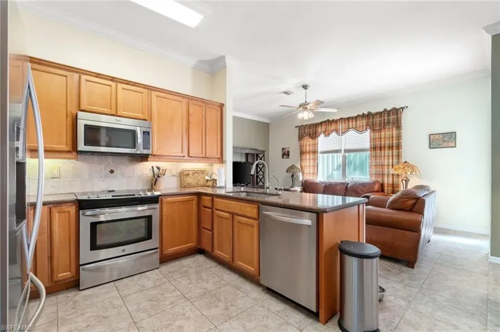Kitchen featuring ceiling fan, appliances with stainless steel finishes, sink, and kitchen peninsula