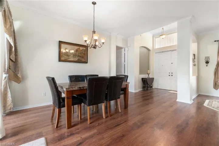 Dining space with dark hardwood / wood-style flooring, an inviting chandelier, and crown molding
