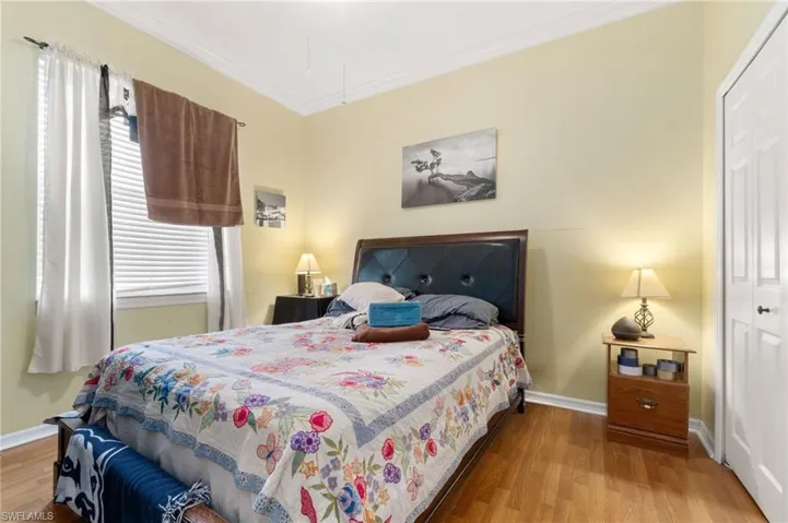 Bedroom featuring crown molding, multiple windows, a closet, and light hardwood / wood-style floors