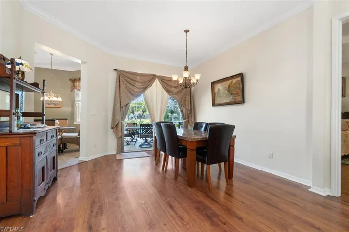 Dining area featuring an inviting chandelier, dark wood-type flooring, and ornamental molding