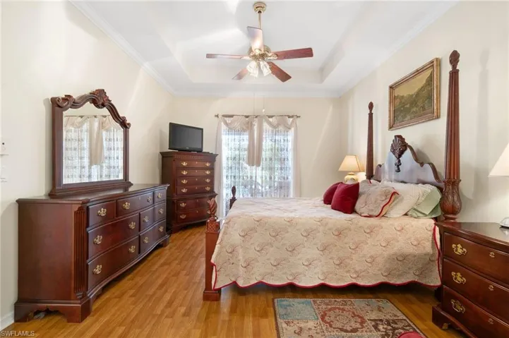 Bedroom featuring ceiling fan, hardwood / wood-style flooring, and a raised ceiling