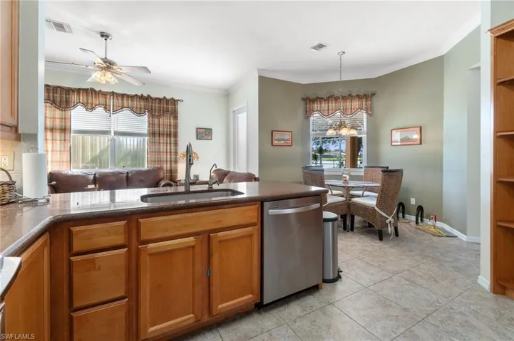 Kitchen with light tile patterned flooring, a healthy amount of sunlight, sink, and stainless steel dishwasher