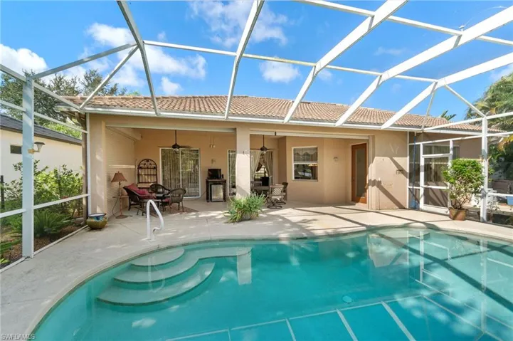 View of swimming pool with glass enclosure, a patio area, and ceiling fan