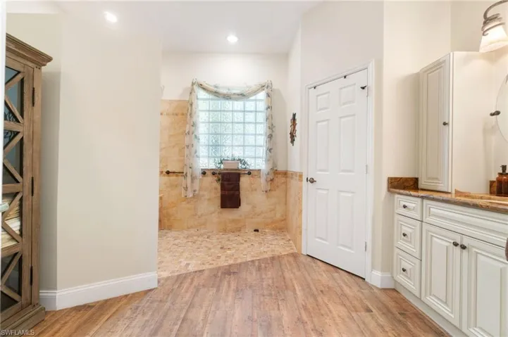 Bathroom with tiled shower, hardwood / wood-style floors, and vanity