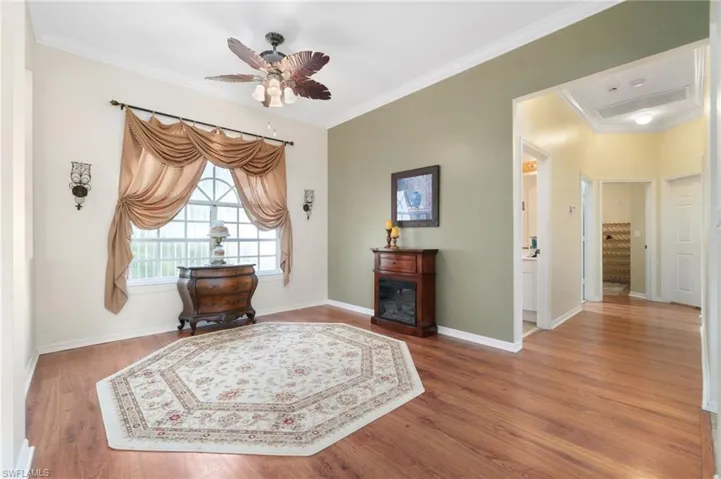 Sitting room with wood-type flooring, crown molding, and ceiling fan