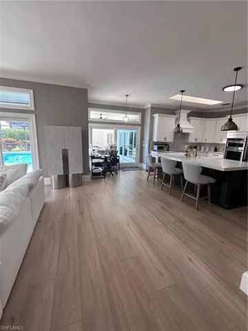 Living room with sink, light hardwood / wood-style floors, and crown molding