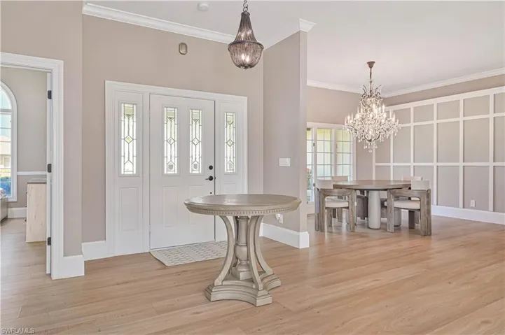 Foyer with a notable chandelier, ornamental molding, and light wood-type flooring