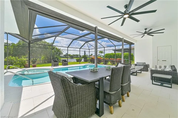View of pool with ceiling fan, glass enclosure, an outdoor living space, and a patio area