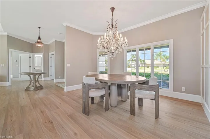 Dining room with light wood-type flooring, a notable chandelier, and crown molding