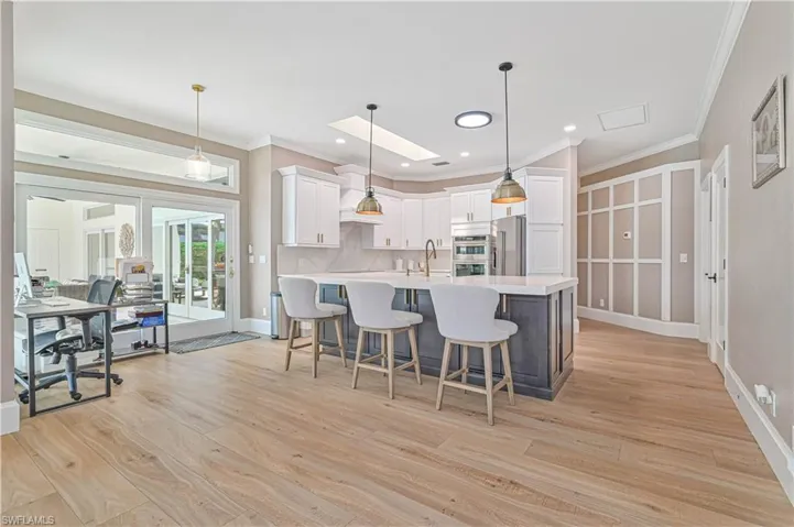 Kitchen with stainless steel appliances, light hardwood / wood-style floors, tasteful backsplash, pendant lighting, and white cabinets