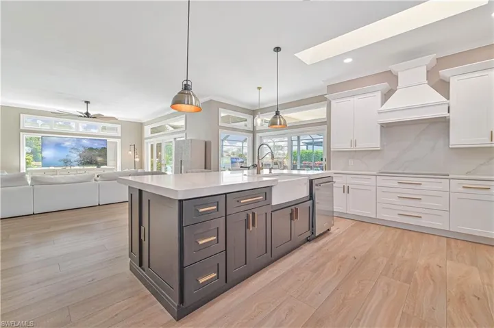 Kitchen with white cabinetry, a wealth of natural light, and custom exhaust hood