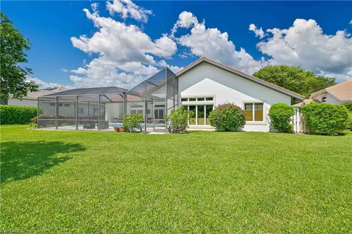 Rear view of house with a yard and a lanai