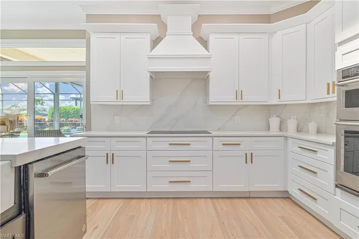 Kitchen featuring white cabinetry, tasteful backsplash, light hardwood / wood-style flooring, and custom range hood