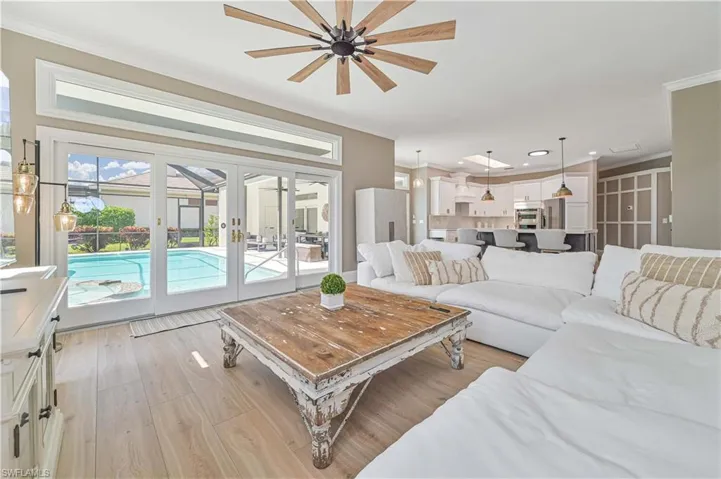 Living room featuring light wood-type flooring, ornamental molding, french doors, and ceiling fan