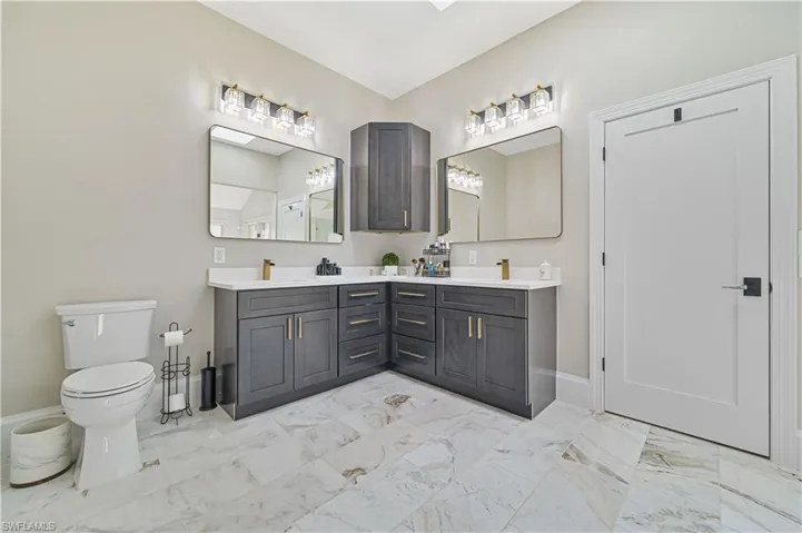 Bathroom featuring tile patterned flooring, toilet, and dual vanity