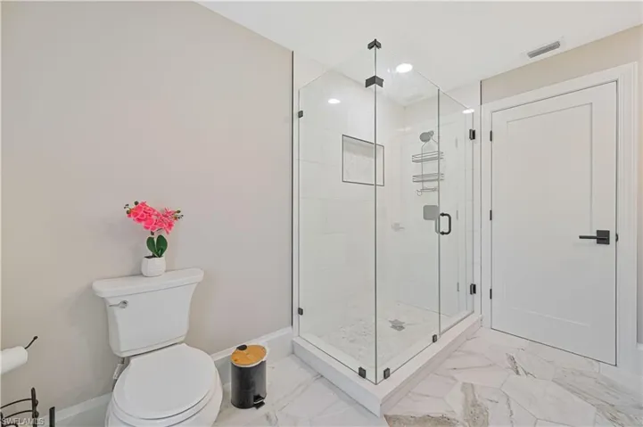Bathroom with tile patterned flooring, toilet, and a shower with door