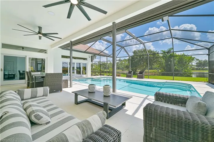 View of swimming pool with glass enclosure, an outdoor living space, ceiling fan, and a patio area