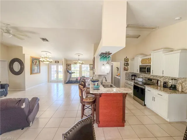 Kitchen with light tile patterned floors, appliances with stainless steel finishes, a breakfast bar, and open floor plan