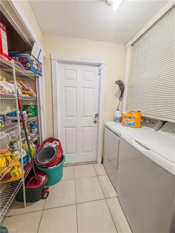 Washroom with washer and dryer, light tile patterned flooring, and laundry area