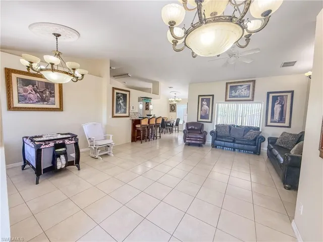 Living area with an inviting chandelier, baseboards, light tile patterned floors, and visible vents