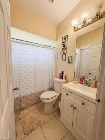 Full bath with tile patterned flooring, a shower with shower curtain, toilet, and vanity