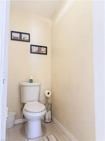 Bathroom featuring toilet, baseboards, and tile patterned flooring