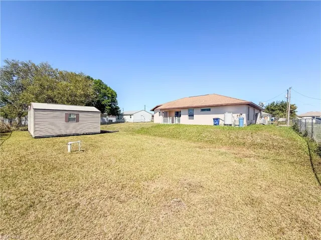 View of yard with fence, an outbuilding, and a shed