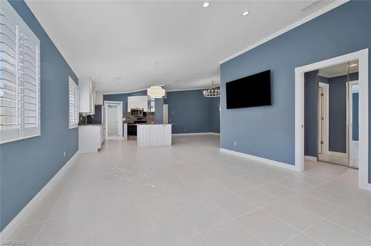 Unfurnished living room featuring ornamental molding, sink, light tile patterned floors, and a chandelier