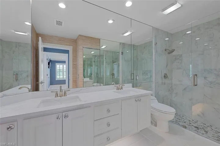 Bathroom with vanity, a shower with door, tile patterned floors, toilet, and tile walls