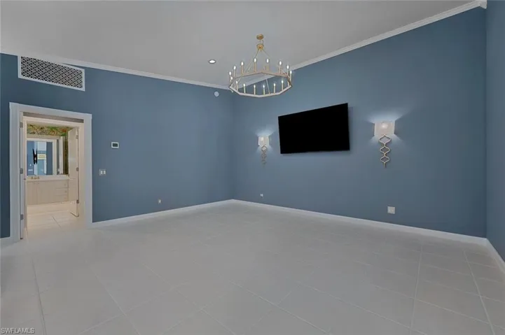 Tiled empty room with a chandelier and ornamental molding