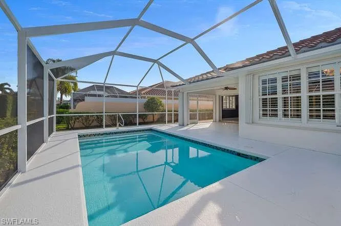 View of pool with a patio, glass enclosure, and ceiling fan