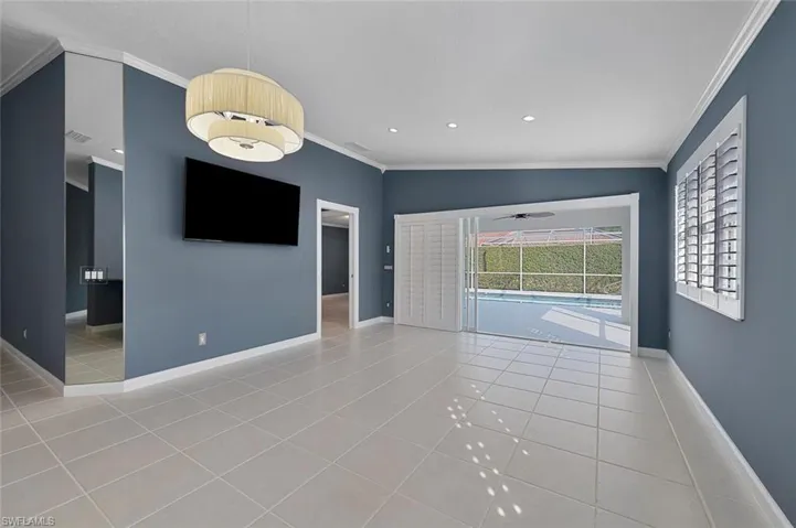 Unfurnished living room featuring crown molding, light tile patterned floors, lofted ceiling, and ceiling fan