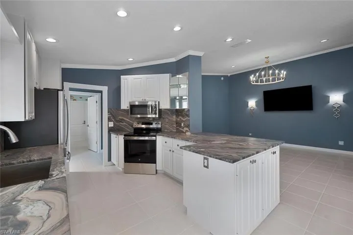 Kitchen featuring white cabinetry, sink, kitchen peninsula, pendant lighting, and appliances with stainless steel finishes