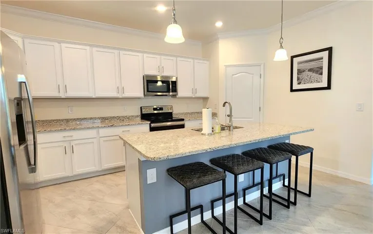 Kitchen featuring white cabinetry, stainless steel appliances, pendant lighting, sink, and light tile patterned floors