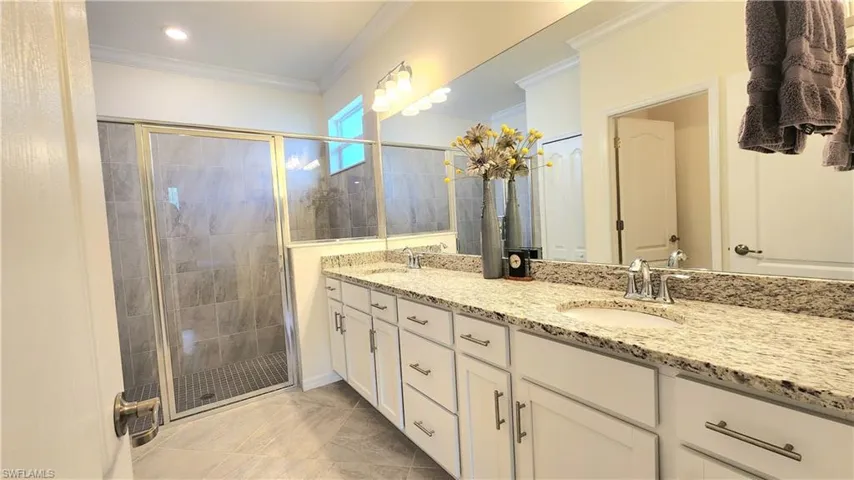 Bathroom with dual vanity, walk in shower, tile patterned flooring, and ornamental molding