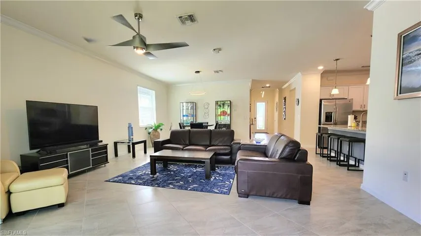 Tiled living room with crown molding and ceiling fan