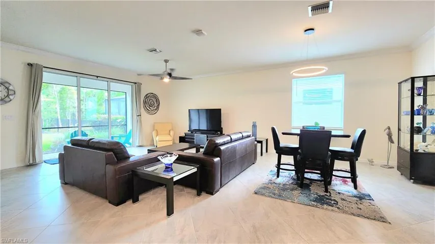 Living room featuring light tile patterned flooring, crown molding, and ceiling fan