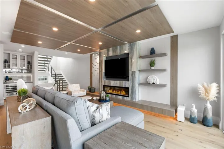 Living area with stairway, light wood-style flooring, wood ceiling, recessed lighting, and a tile fireplace
