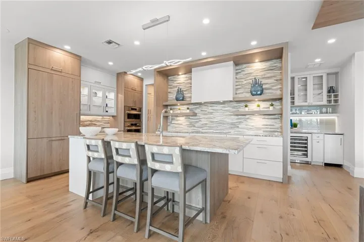 Kitchen featuring modern cabinets, open shelves, backsplash, light stone countertops, and glass insert cabinets