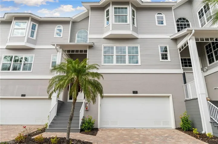 View of front of property with stairway, a garage, and decorative driveway