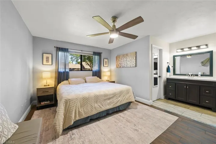 Bedroom with ceiling fan, ensuite bathroom, sink, and light wood-type flooring