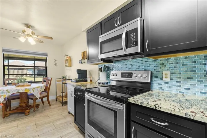 Kitchen featuring ceiling fan, appliances with stainless steel finishes, light stone countertops, and backsplash