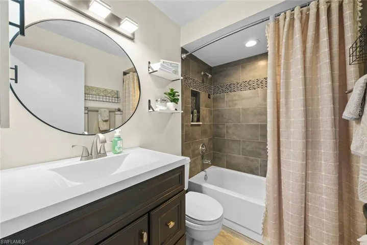 Full bathroom with shower / bath combination with curtain, vanity, and toilet
