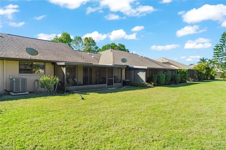 Back of property featuring central AC unit, a lawn, and a sunroom