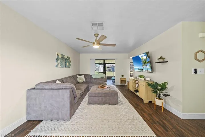 Living room with ceiling fan and dark hardwood / wood-style floors